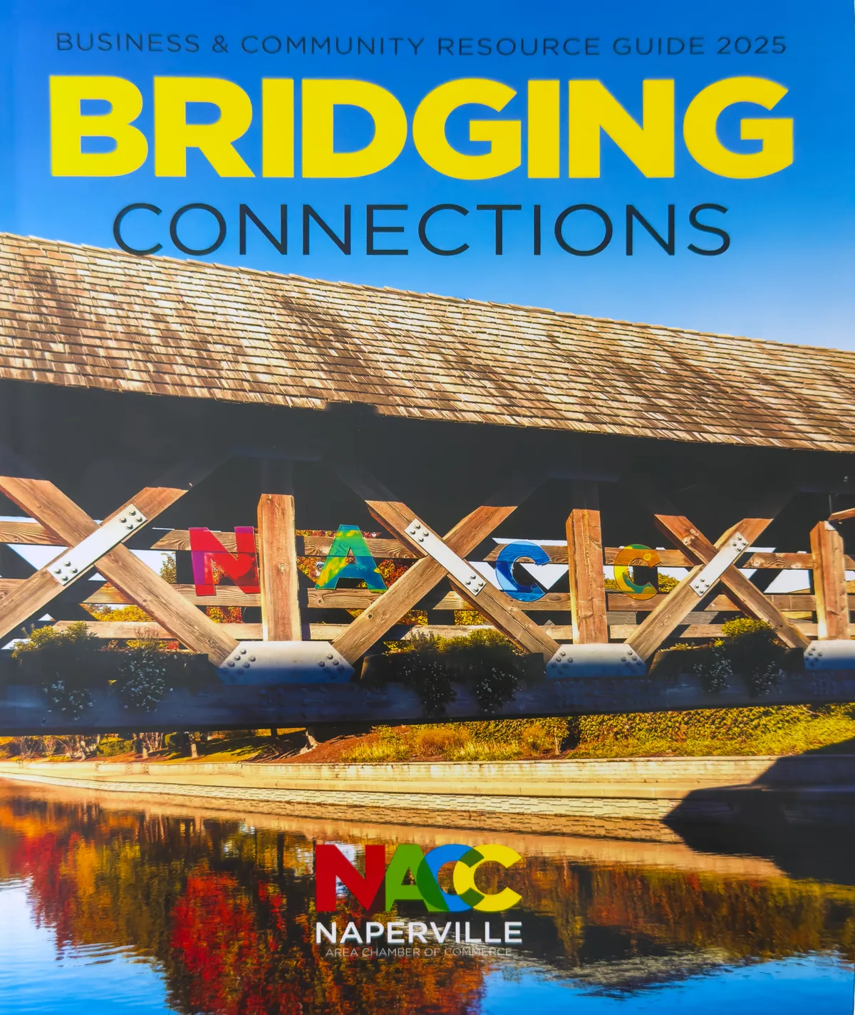 Guide cover: translucent colored letters spelling NACC in the trusses of the Riverwalk covered bridge.