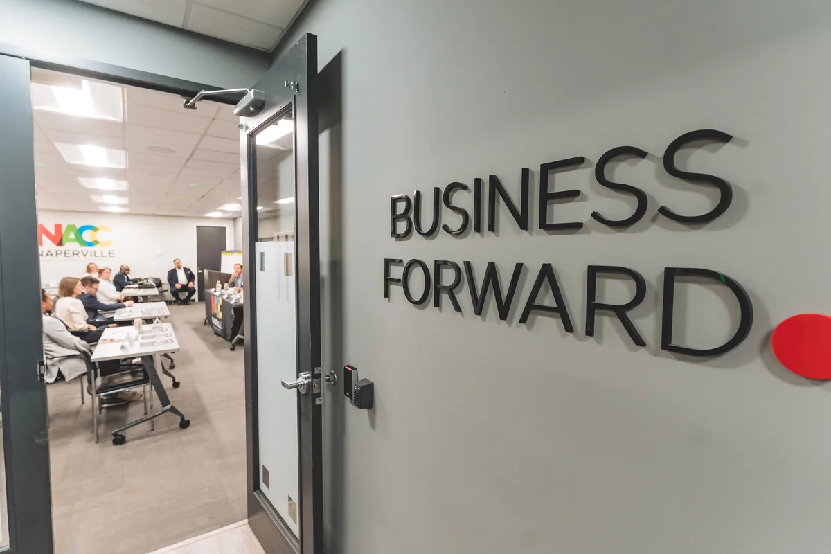 Raised black letters reading Business Forward mounted on the grey wall of an office.