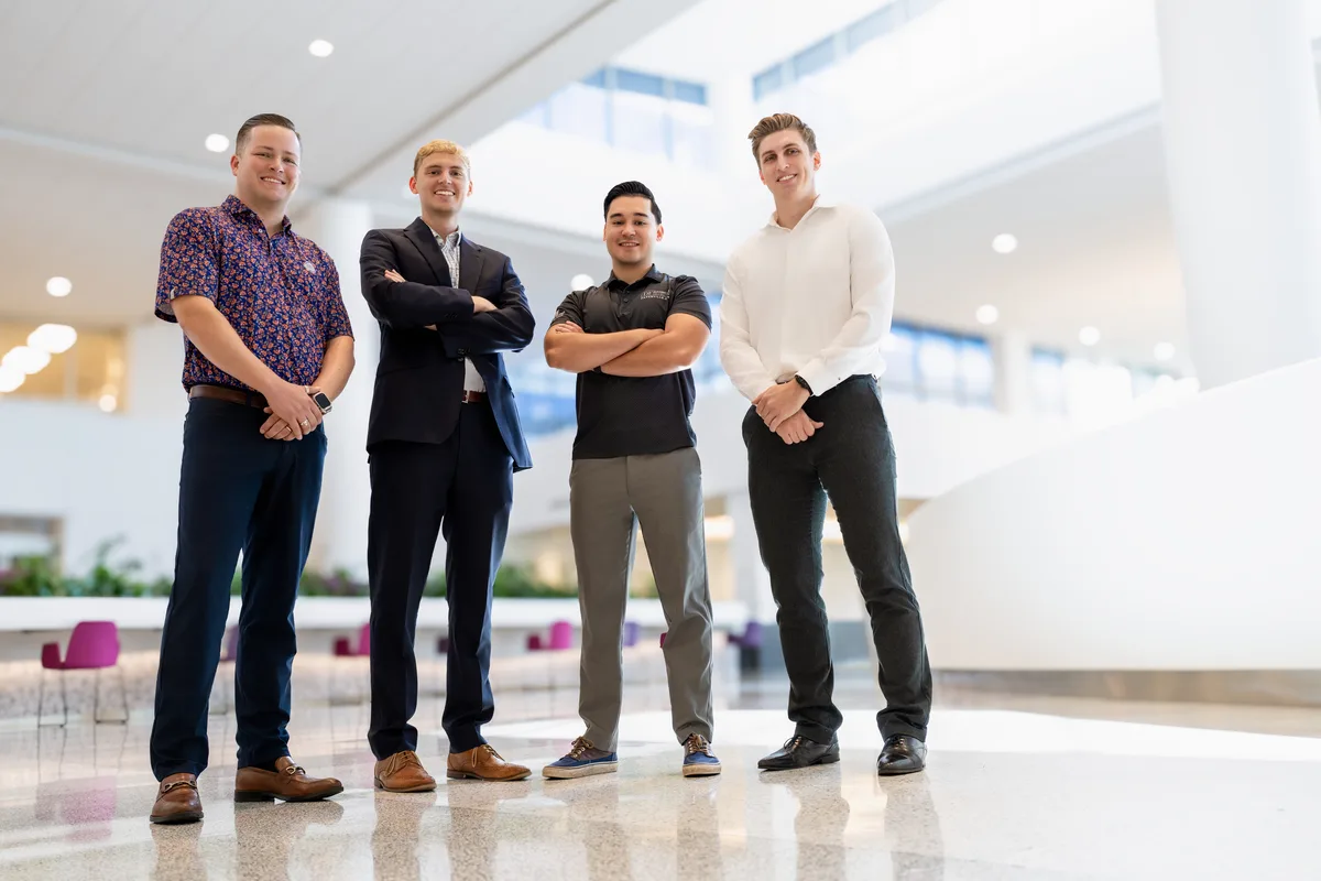 Four young professionals stand together in a bright, airy atrium.