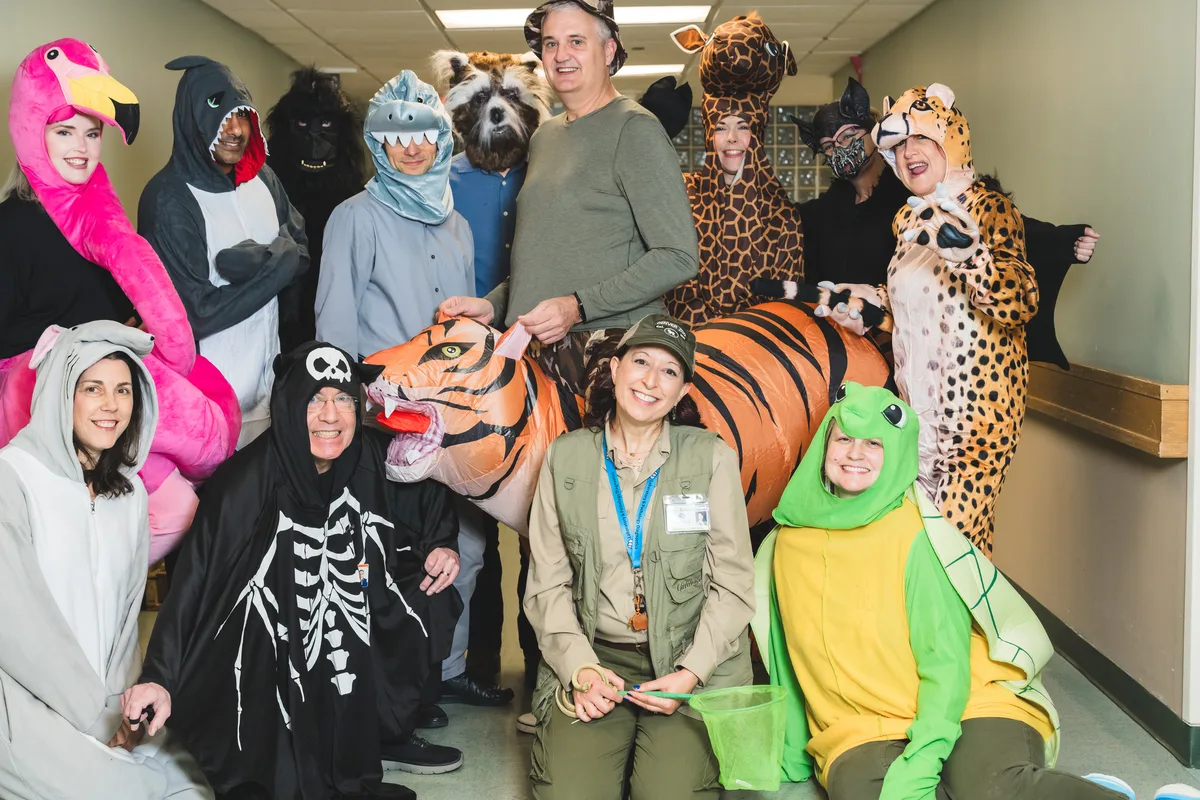 The same laboratory team in costume, photographed together in a hospital hallway against a plain wall.