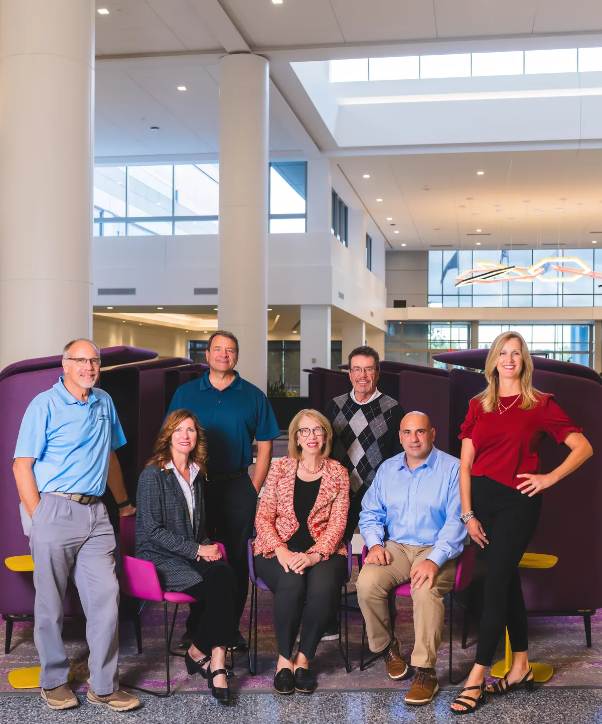 A full team photographed together in their office, standing and seated across two rows.