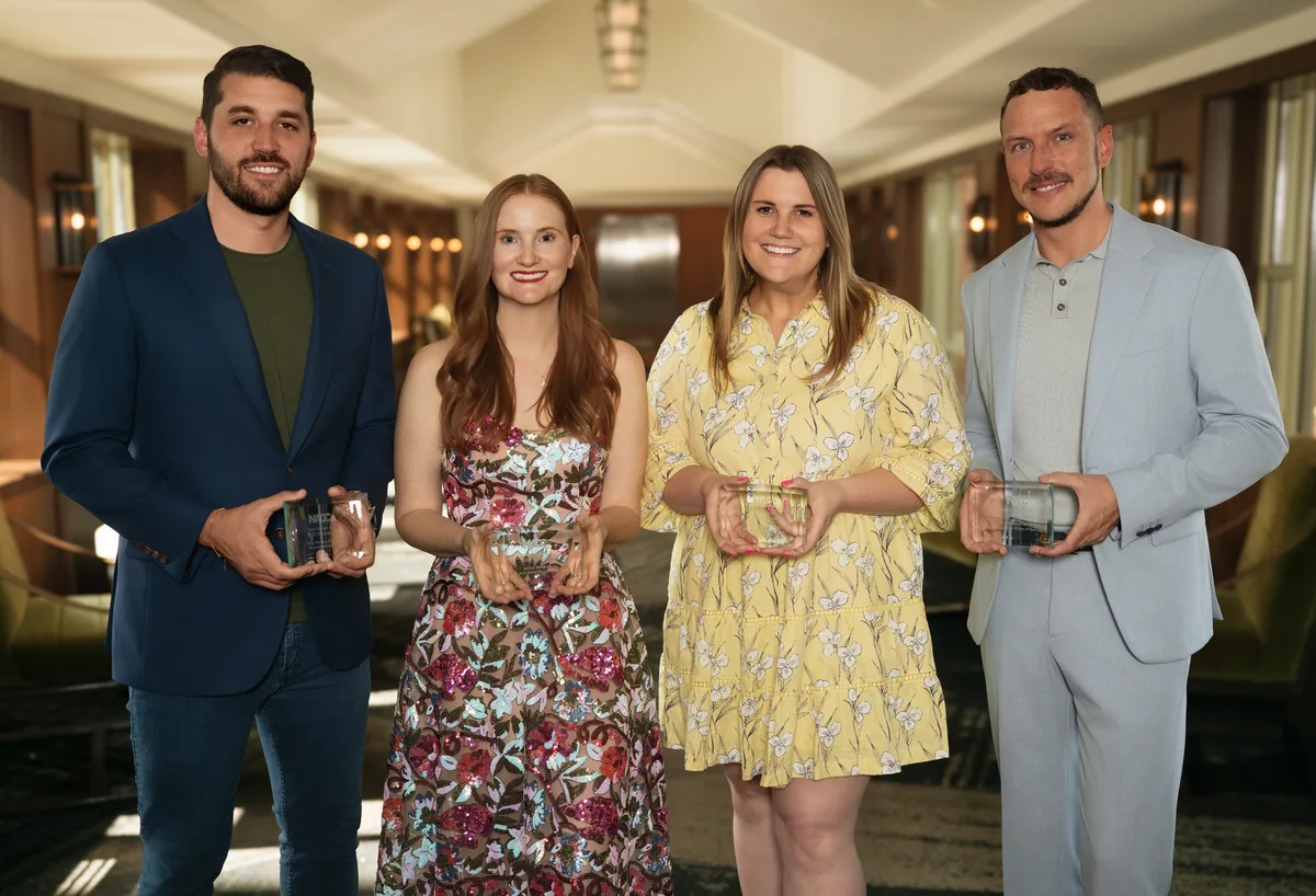 Four award winners standing together, each holding a glass award.