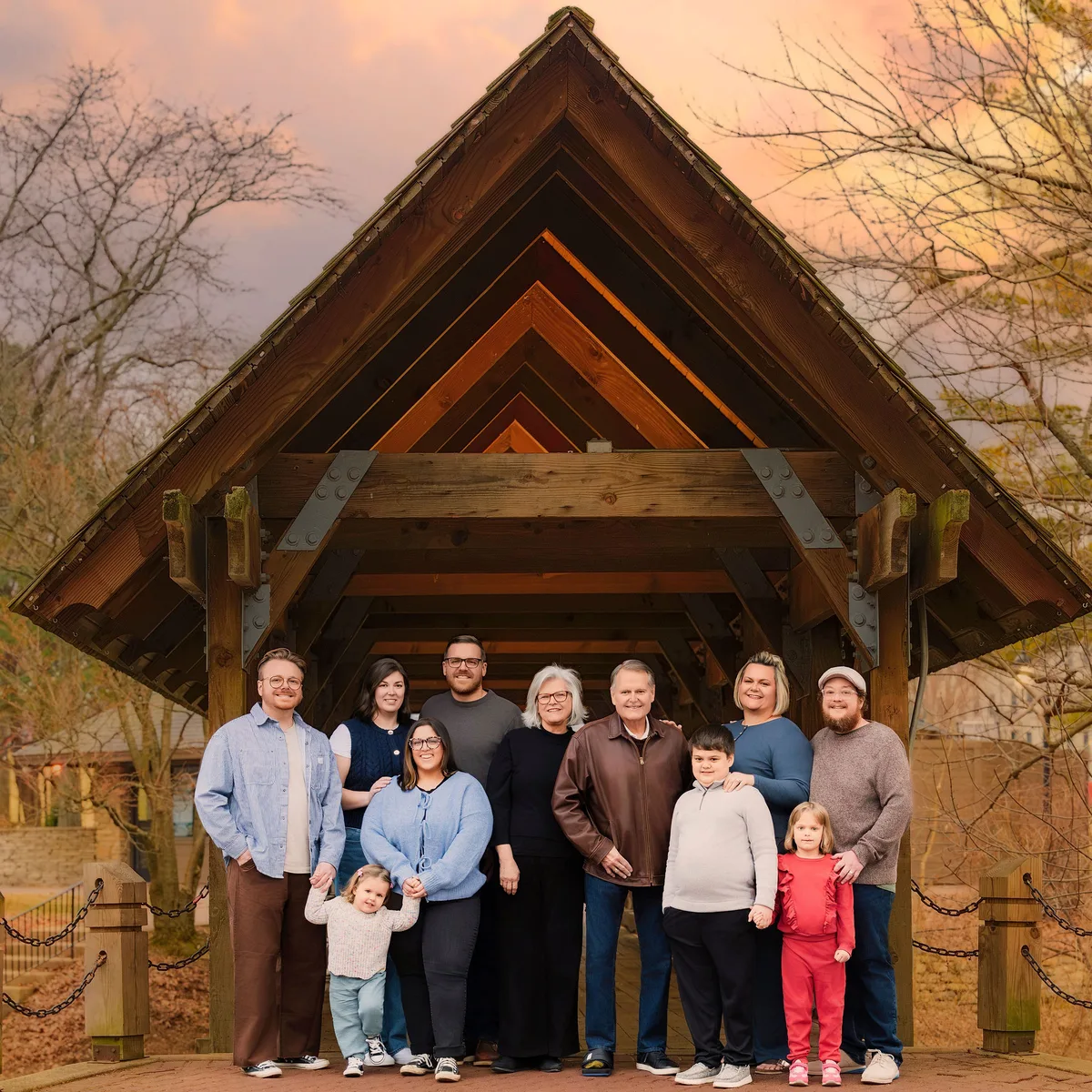 Three generations of one family stand together under the Riverwalk covered bridge on a winter evening.
