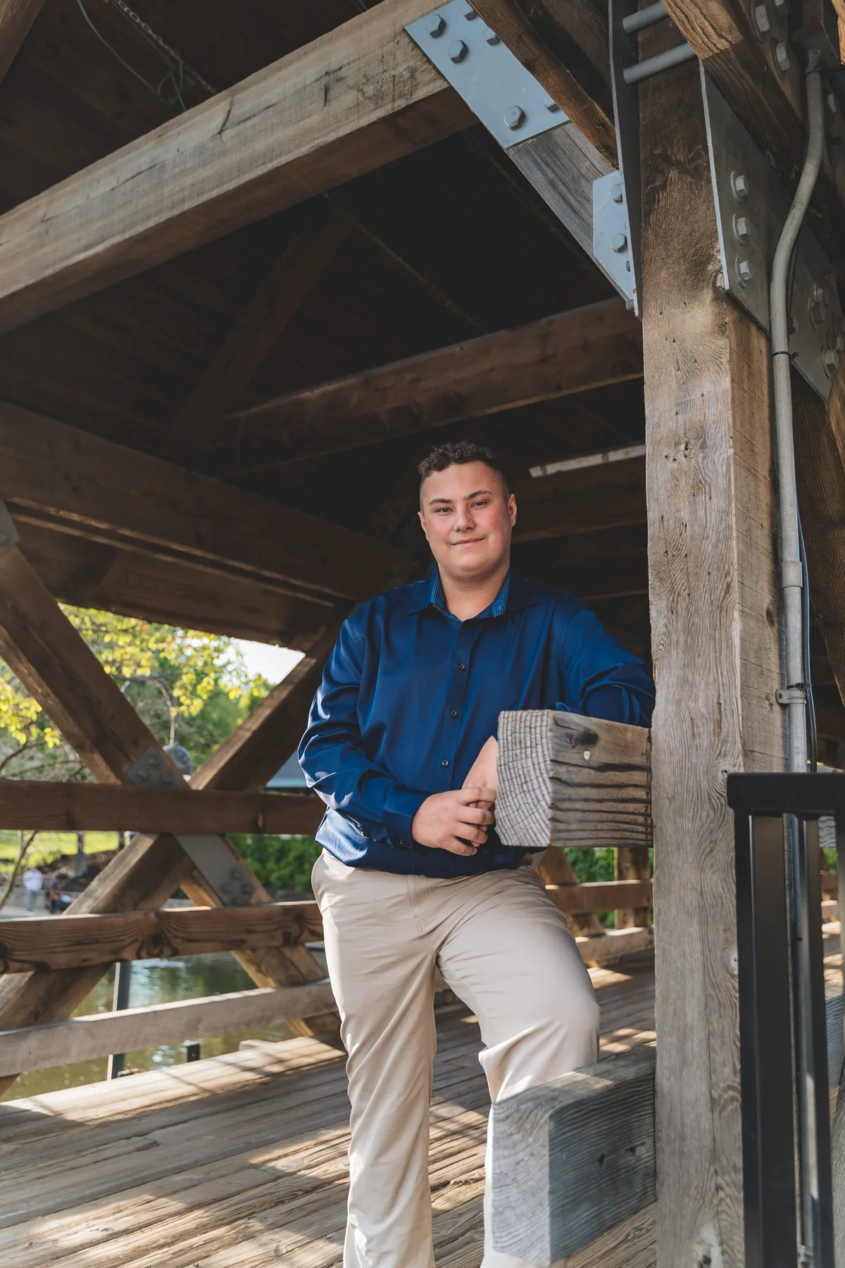 A high school senior leans on a post inside the covered bridge on the Naperville Riverwalk.