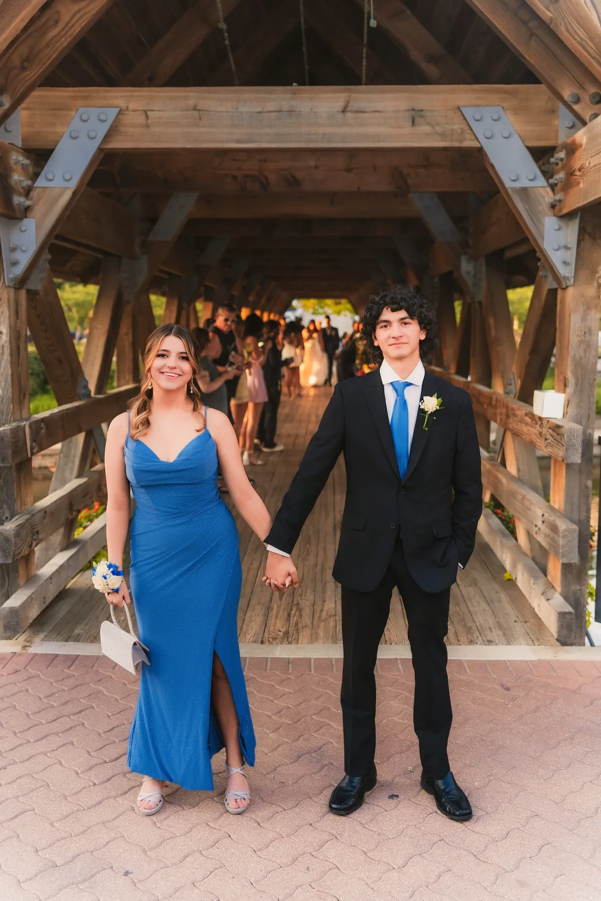 A homecoming couple holds hands inside the covered bridge on the Naperville Riverwalk.