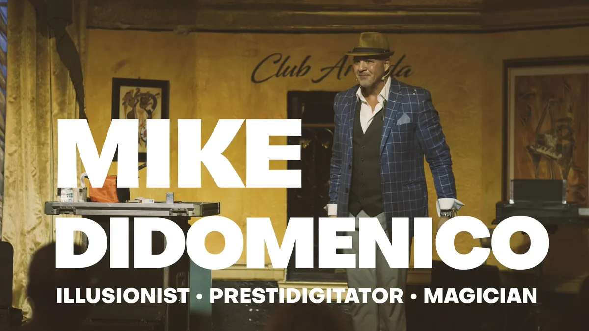 Title card of Mike DiDomenico's promo video: Mike on a club stage in a fedora, his name set large across the frame.