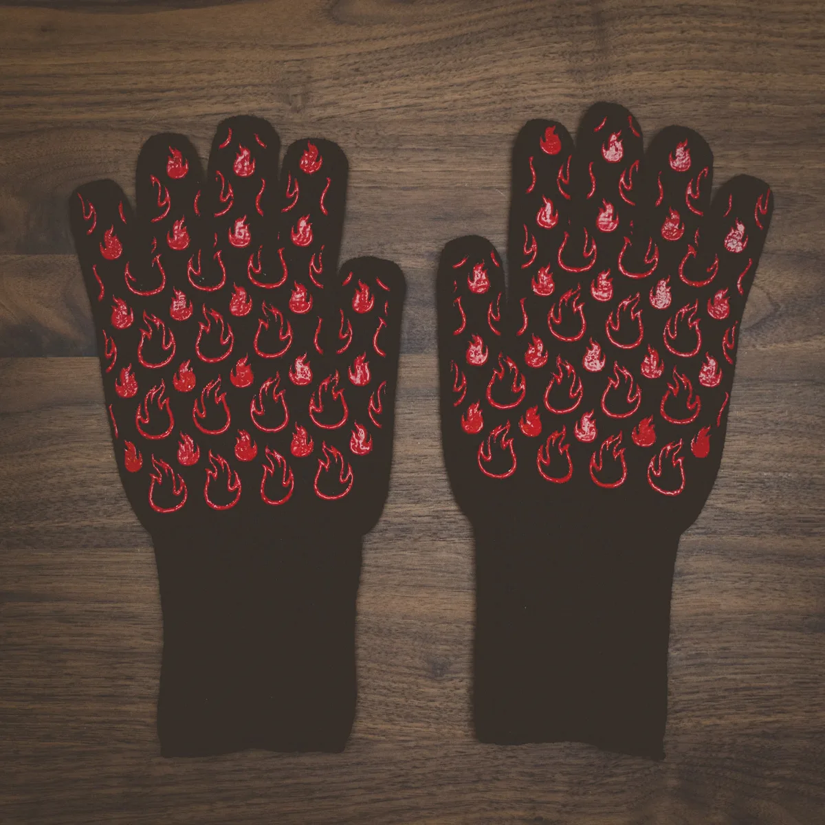 A pair of black grill gloves with a red flame pattern.